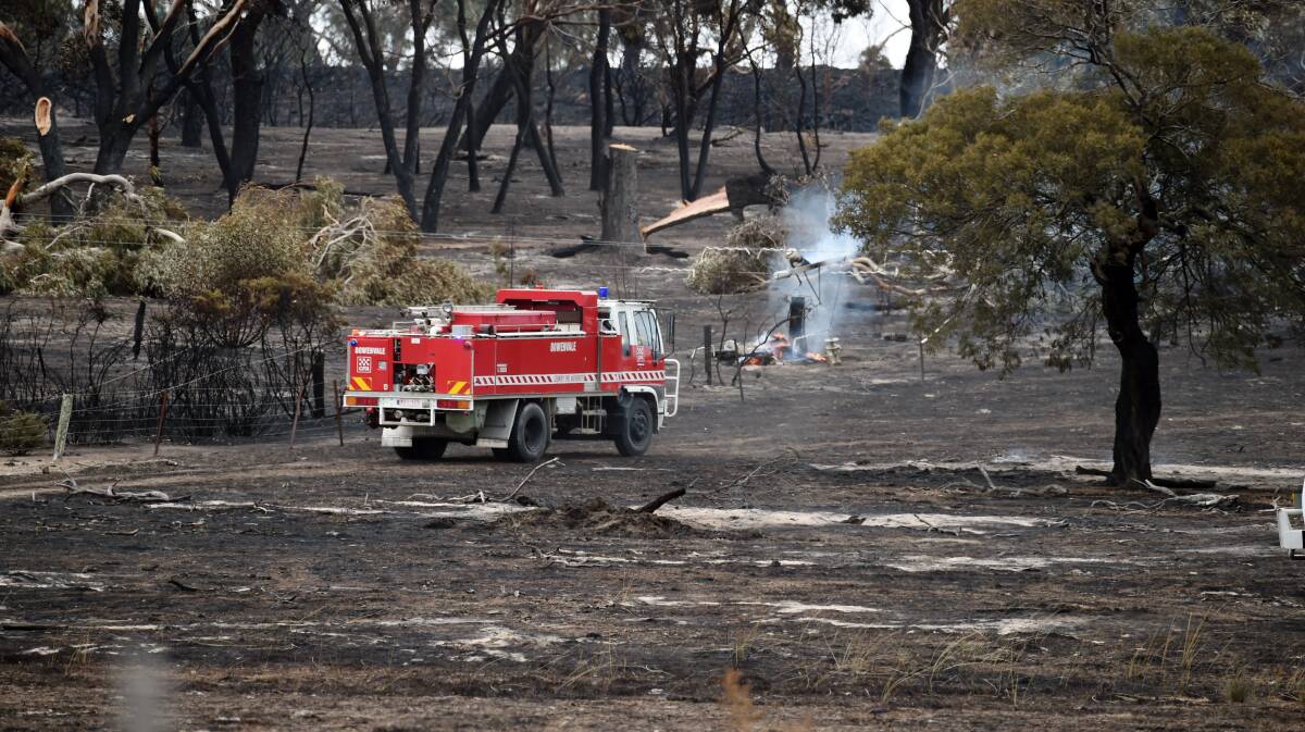 CHARRED: Firefighters make their way across the charred paddocks during mopping up operations after the blaze. Picture: Kate Healy