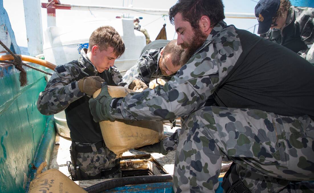 Able Seaman Electronic Warfare Justin Springer (left) and Leading Seaman Marine Technician Daniel Colliver remove sacks containing suspected narcotics
during a search of a suspicious dhow by HMAS Ballarat's Boarding Party. Picture: Australian Defence Force