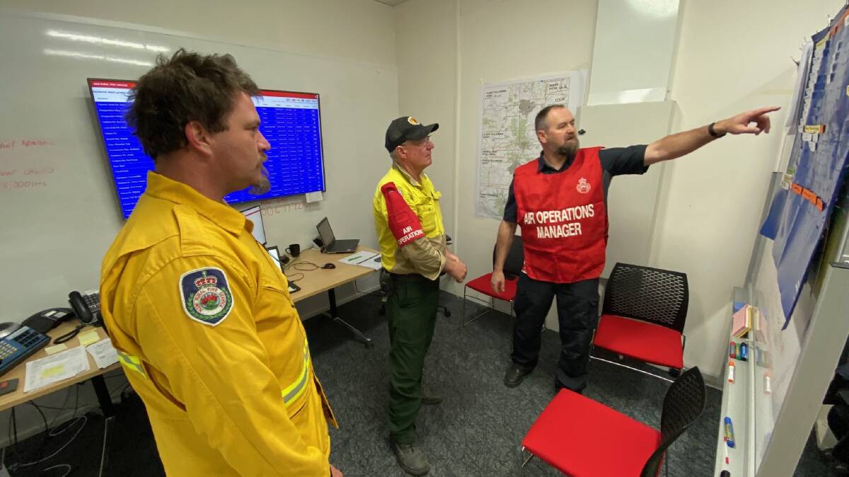 CONTROL: Wayne Rigg (in red) works with firefighters and volunteers coordinating the air bombers in Northern New South Wales. Picture: Wayne Rigg