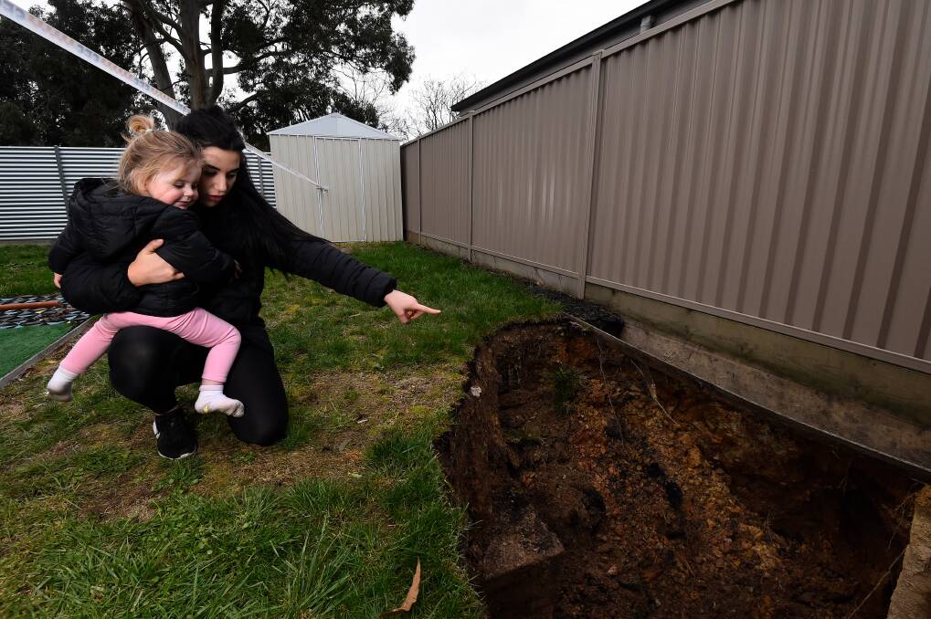 COLLAPSE: Theonie Konstantinea and daughter Armani survey the damage to their backyard after the mine shaft collapse on Wednesday. Picture: Adam Trafford