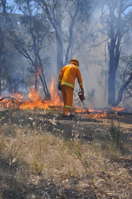 BURN: A CFA member lights the fire. Photo: Bill Cook