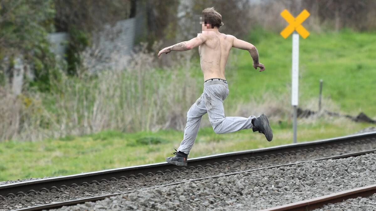 The man escapes across the railway tracks. Photo: Lachlan Bence.