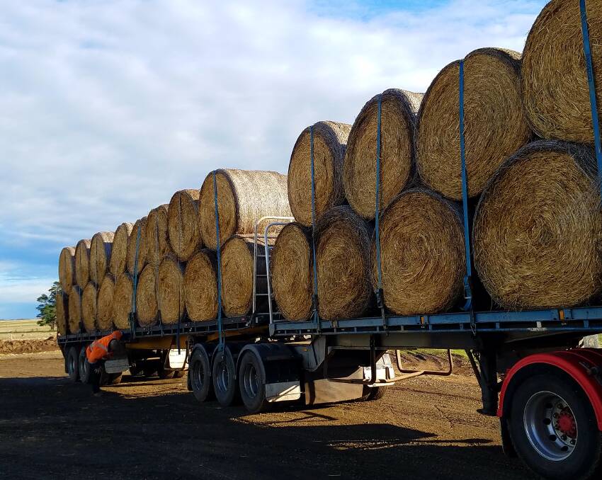 PRECIOUS LOAD: A truck loaded with 52 hay rolls of oaten hay has a final check before  heading to drought-stricken NSW. Photo: Leanne Younes