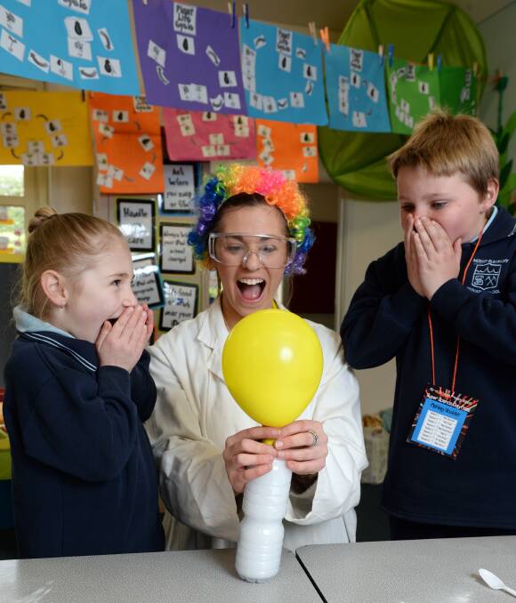 EXPERIMENTING: Mount Pleasant prep student Sophie Jelly and grade three student Ashley Hodder watch on with excitement as teacher Jane De Lorenzo blows a balloon up using gas created in a bottle. Picture: Kate Healy