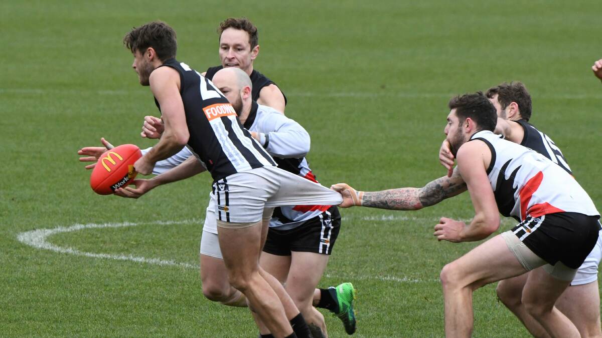 Despite getting a high tackle from Darren leoard (Darley), North Ballarat City's Will Young does his best slwo down Shane Page. Picture: Lachlan Bence