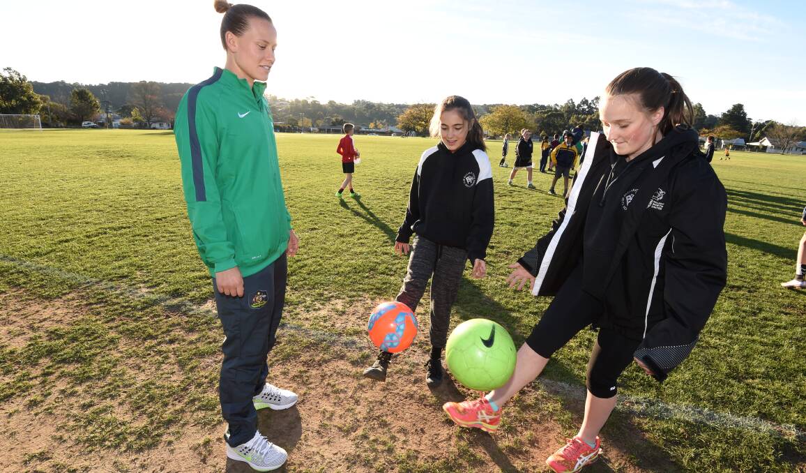 Matildas midfielder Emily Van Egmond shares some foot skills with North United under-13 players Eva Costa and Maybelle Wood on Tuesday.