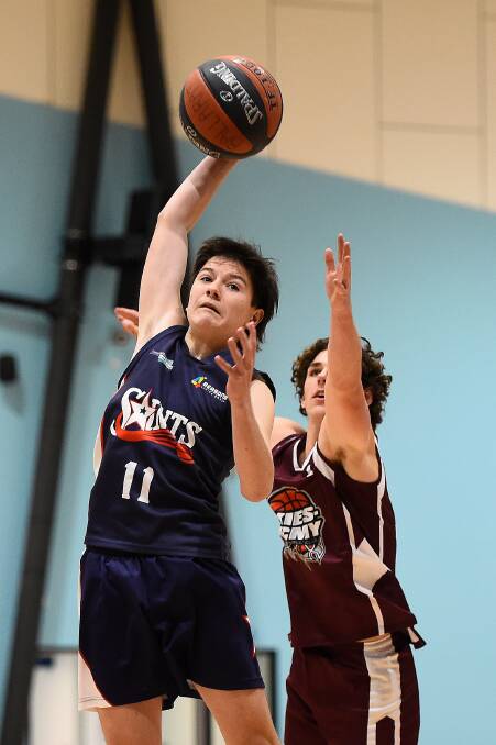AT FULL STRETCH: Noah Shearer (Saints) keeps the ball out of the reach of Hugh Bond (Exies. Acmy) in an under-19 basketball encounter. Picture: Adam Trafford.