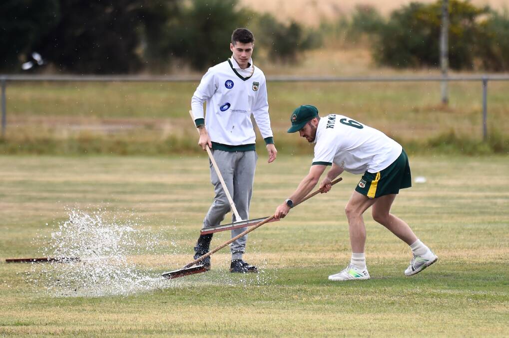 Dylan York (left) and Corey Hucker of Napoleons Sebastopol attempt to clear some water as umpires assess whether to continue play due to the rain. Picture by Adam Trafford.