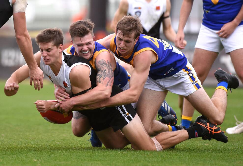 Harry Loader of North Ballarat is tackled by Benjamin Trew (middle) and Hugo Papst of Sebastopol. Picture: Adam Trafford