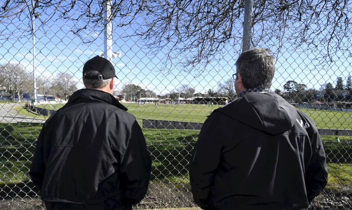 Spectators try and peer through the fence at a closed-off Eastern Oval. Picture: Lachlan Bence