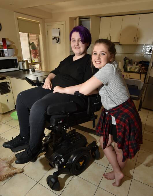HEIGHT: Milly Yeoman jokes around, raising her wheelchair to be taller than her best mate Tilly Burke. Picture: Jeremy Bannister