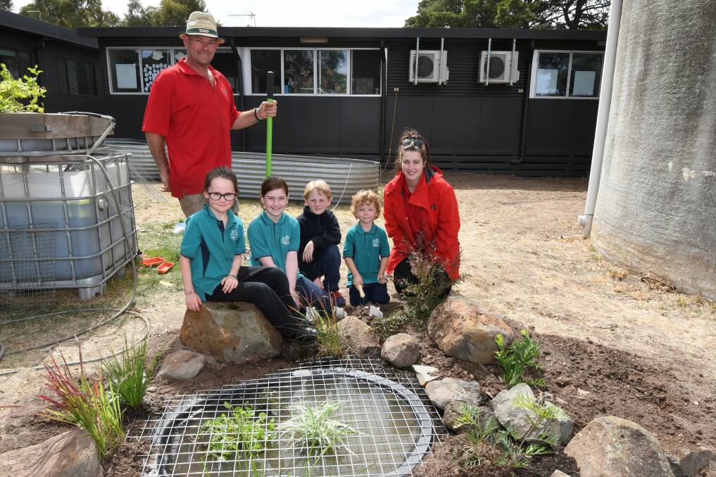 ENVIRONMENT: Bunnings staff Michael Cranford and Maddy Bertram with Cape Clear pupils Violet, Marley, Kyle, Oliver and the new frog pond. Picture: Lachlan Bence.