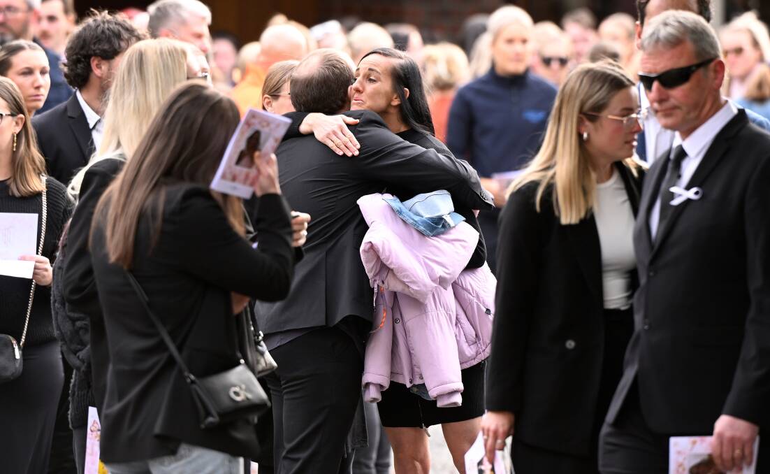 Mourners including Emily Faneco, a former teacher of Hannah McGuire's, embrace after the service. Picture by Adam Trafford