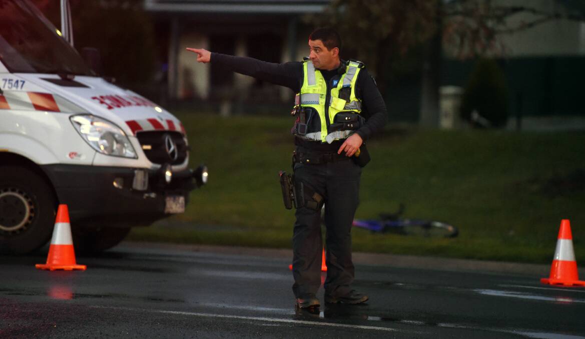 WET NIGHT: A police officer directs traffic around the accident scene, with the crumpled bike on the roadside behind him. Picture: Kate Healy