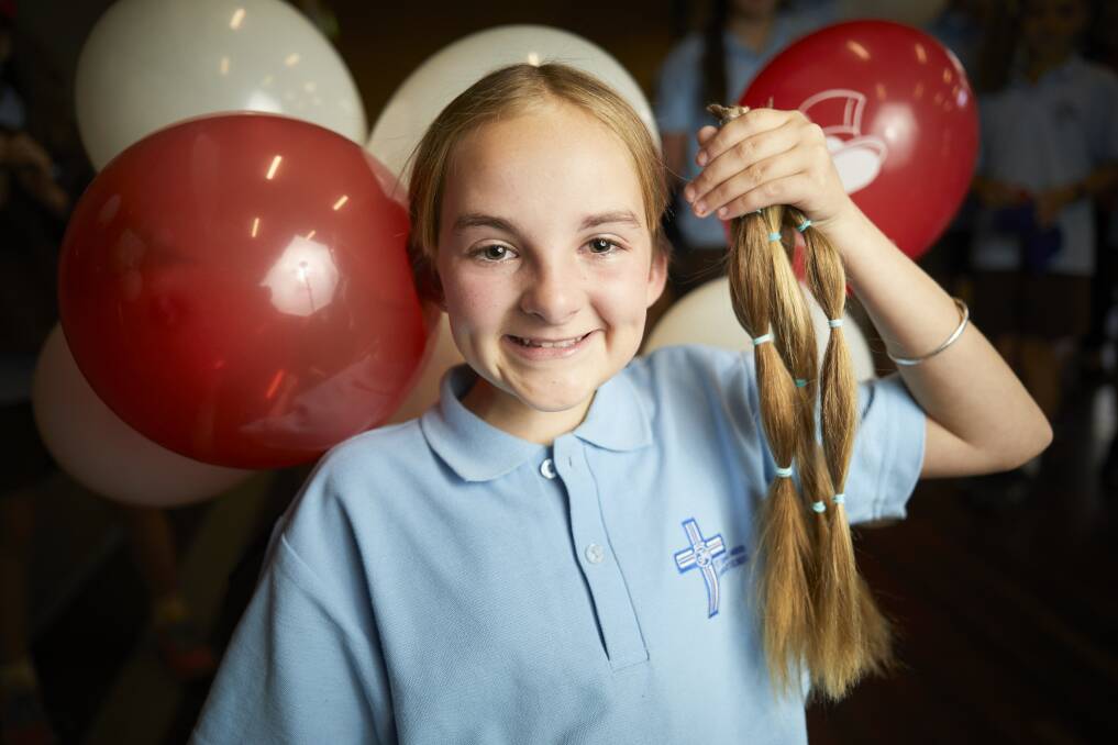 CHOP: St Thomas More pupil Tegan Pickles with her long ponytails that she cut off to donate to be made in to wigs for children with cancer, and to raise money for cancer support networks. Picture: Luka Kauzlaric