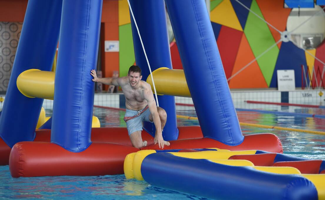 AQUATIC FUN: BALC lifeguard team leader Chris Delahunty gets his balance after swinging on the rope swing as he tackles the new 34m long inflatable obstacle course.