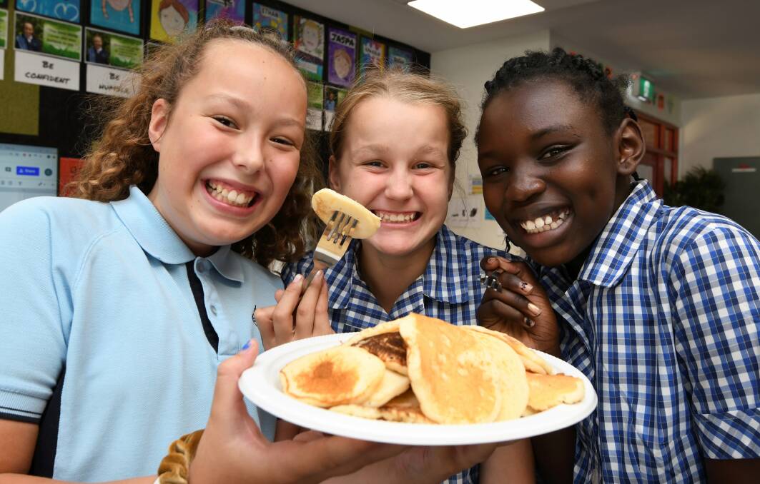 PANCAKES: Lumen Christi Primary School senior students Macey, Bonnie, and Naomi enjoy a serve of Shrove Tuesday goodies. Picture: Lachlan Bence