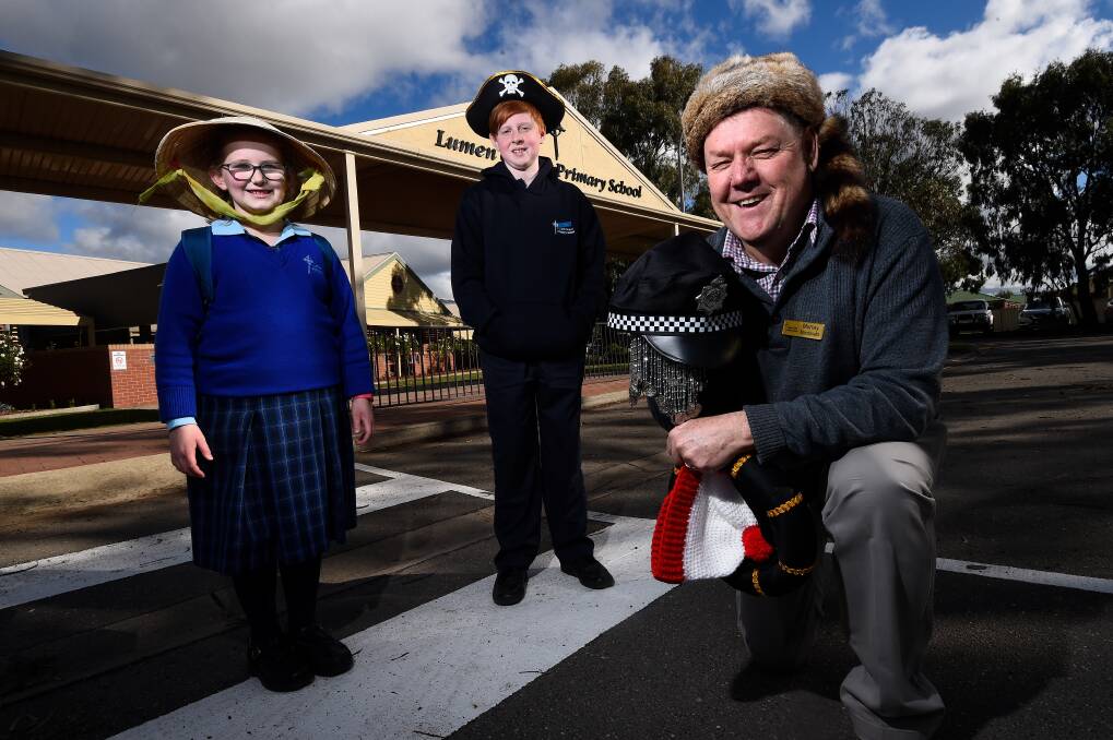 FUN: Lumen Christi Primary School pupils Samantha and Marcus share in the hat fun with principal Murray Macdonald who has donned a different hat every day this term. Picture: Adam Trafford
