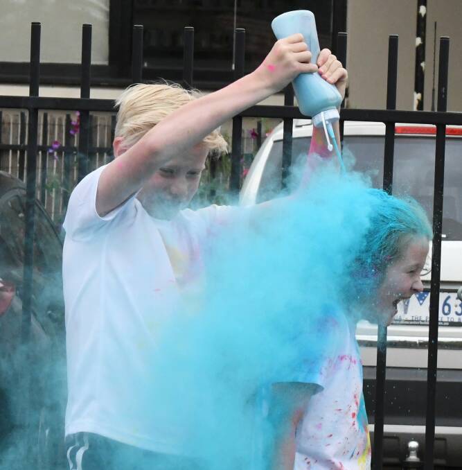 COLOUR: Taj douses Mia with coloured flour after she completes a circuit during the annual Urquhart Park Primary School colour lapathon. Picture: Lachlan Bence
