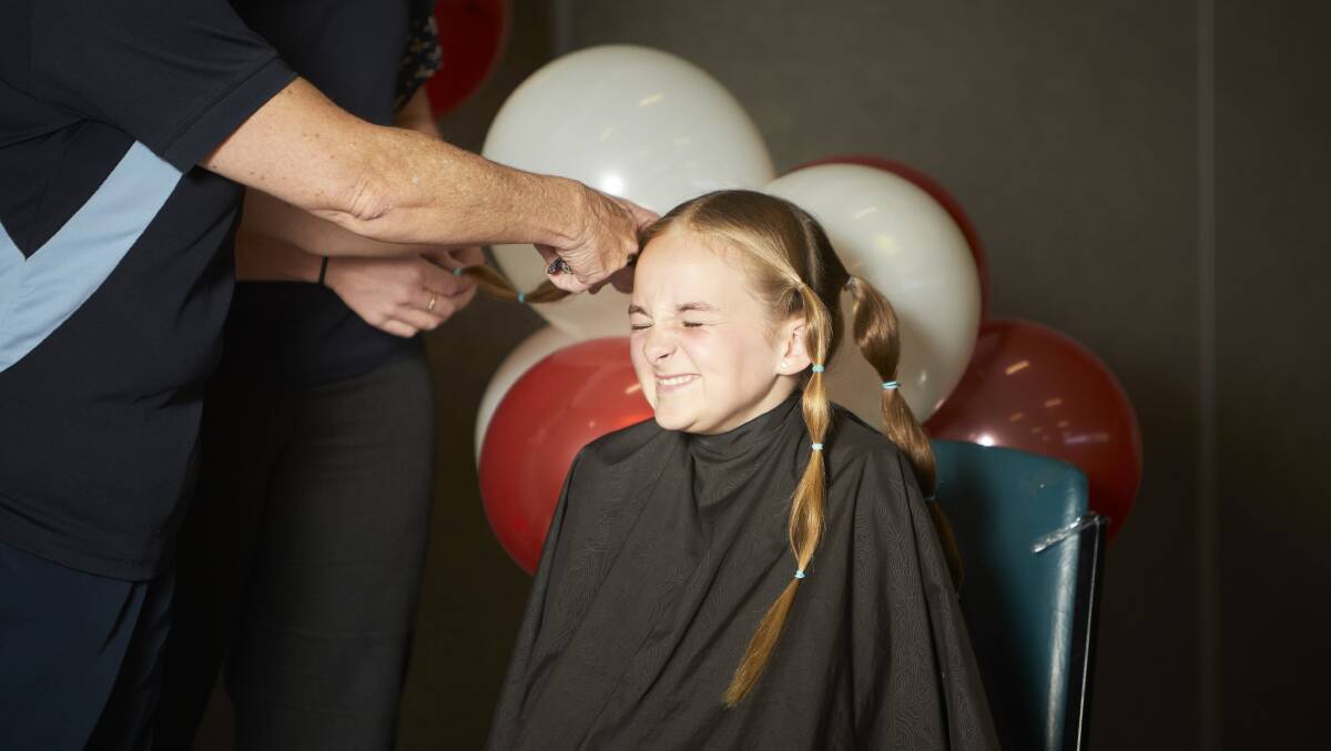 ANTICIPATION: St Thomas More pupil Tegan Pickles winces as the first of her long ponytails is chopped off to donate to be made in to wigs for children with cancer, and to raise money for cancer support networks. Picture: Luka Kauzlaric