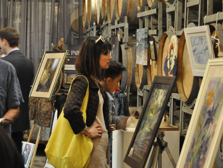 Art lovers inspect paintings at a studio open as part of the Golden Plains Arts Trail