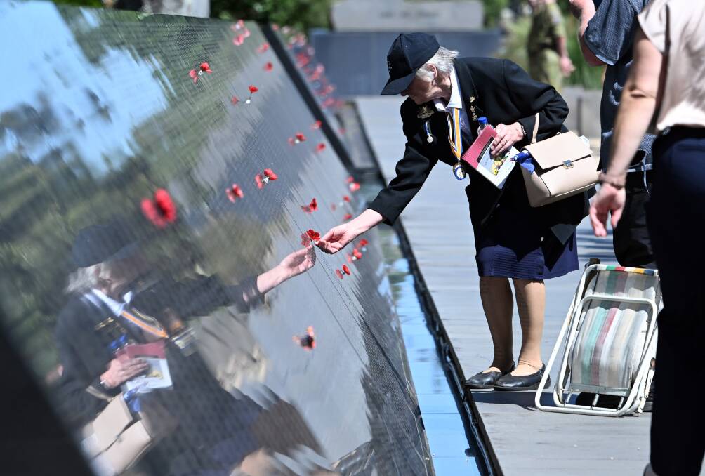A woman places a poppy on one of the 36,400 names on the Australian Ex-Prisoners of War Memorial in Ballarat's South Gardens on Sunday, February 11, 2024. Pictures by Kate Healy