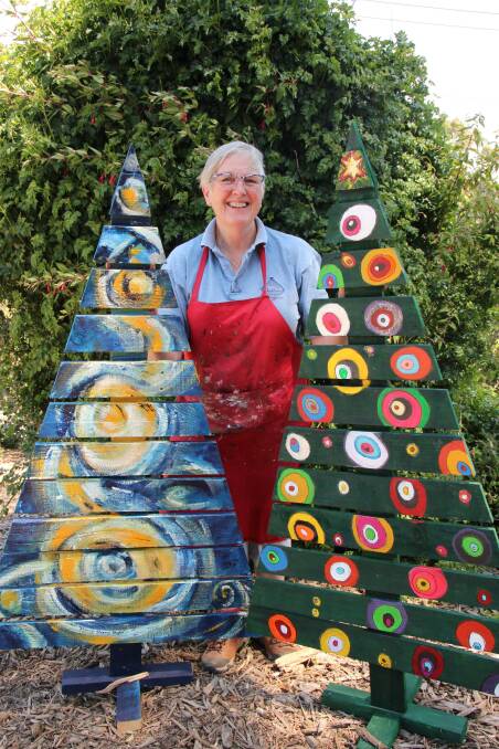 MERRY: Buninyong artist Trudy Nichols with two of the Christmas trees decorated and sold as part of the Buninyong Christmas Tree exhibition last year. Picture: supplied