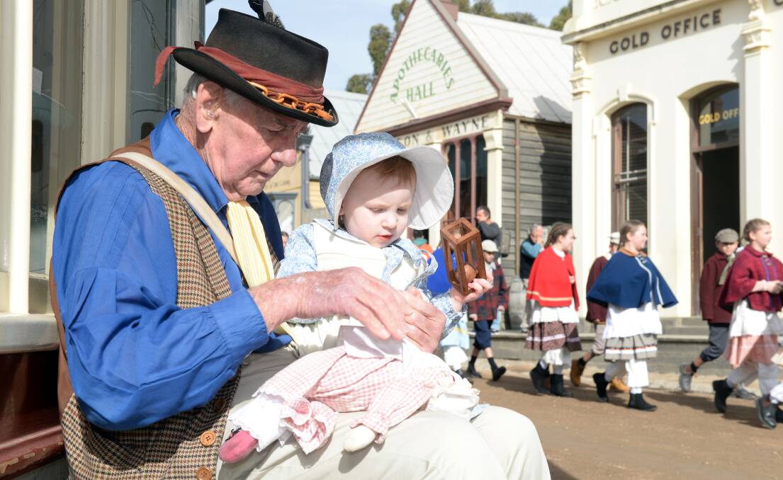 LIVING HISTORY: Sovereign Hill's oldest volunteer Bill Llewellyn, 91, and youngest Abigail Holmes, 2, take a break in the main street during National Volunteers Week. Picture: Kate Healy