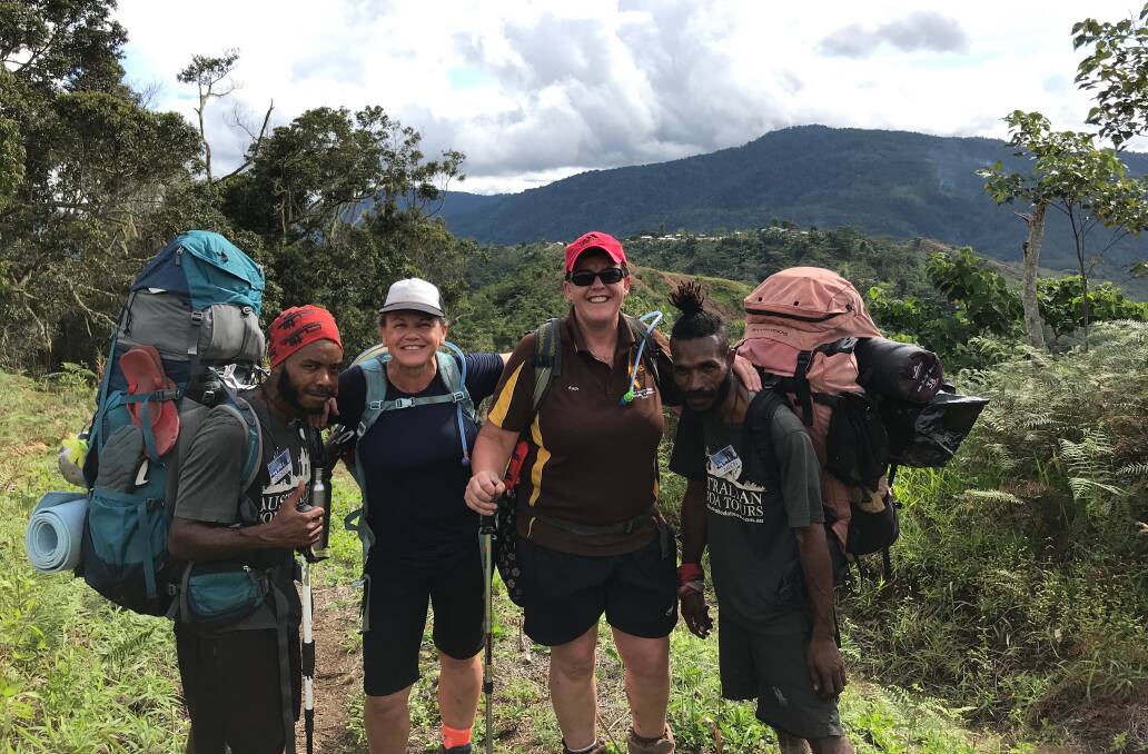 HELPERS: Liz Crothers and sister Kathy with Kokoda Track porters Georgie (left) Aaron (right) high in the mountains of the Owen Stanley Ranges.