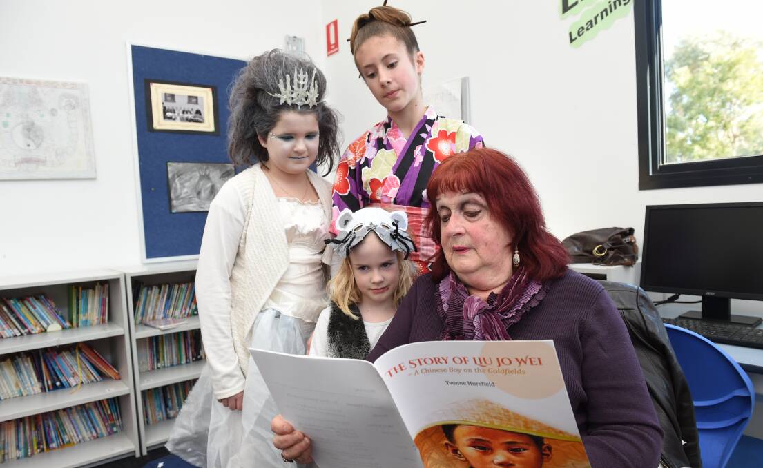 NEW STORY: Imogene, Mackenna and Hanna get a sneak peek of author Yvonne Horsfield's new book The Story of Lui Jo Wei, which is set on the goldfields of Little Bendigo near where their school now sits. Picture: Kate Healy