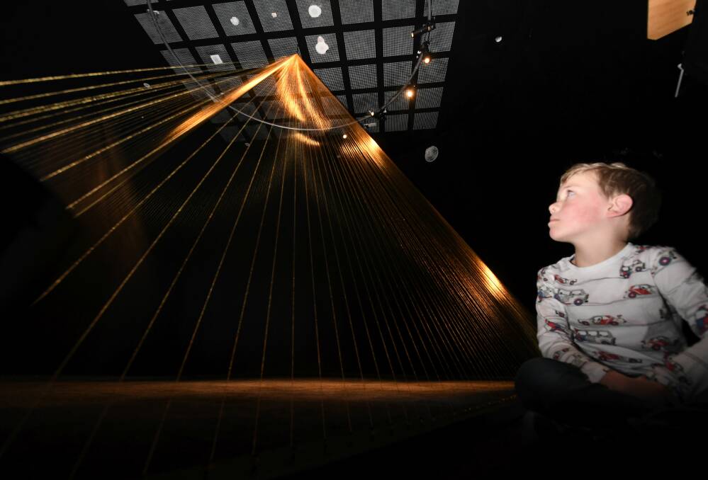 GOLDEN: Flynn Sullivan gets an early look at Ken and Julia Yonetani's 5m tall pyramid created from 24 carat gold thread at the Eureka Centre. Picture: Lachlan Bence