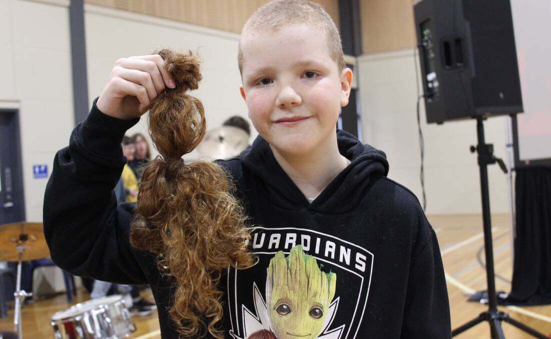 AFTER: Eli Spielvogel shows off his newly shaved head, and his long tresses that will be donated to make wigs for children with cancer. Picture: Sarah Boswell