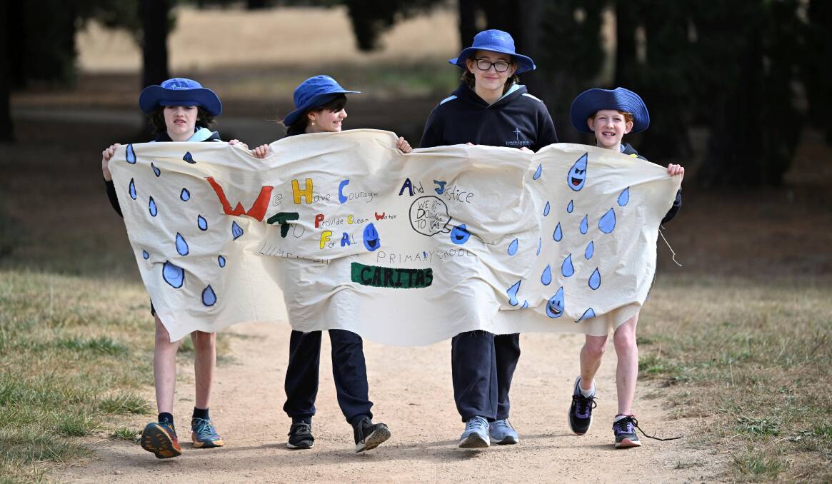 Lumen Christi walkathon Project Compassion appeal leaders Sebastian, Poppy, Samantha, and Morgan with the banner they carried from school to Victoria Park. Picture by Lachlan Bence 