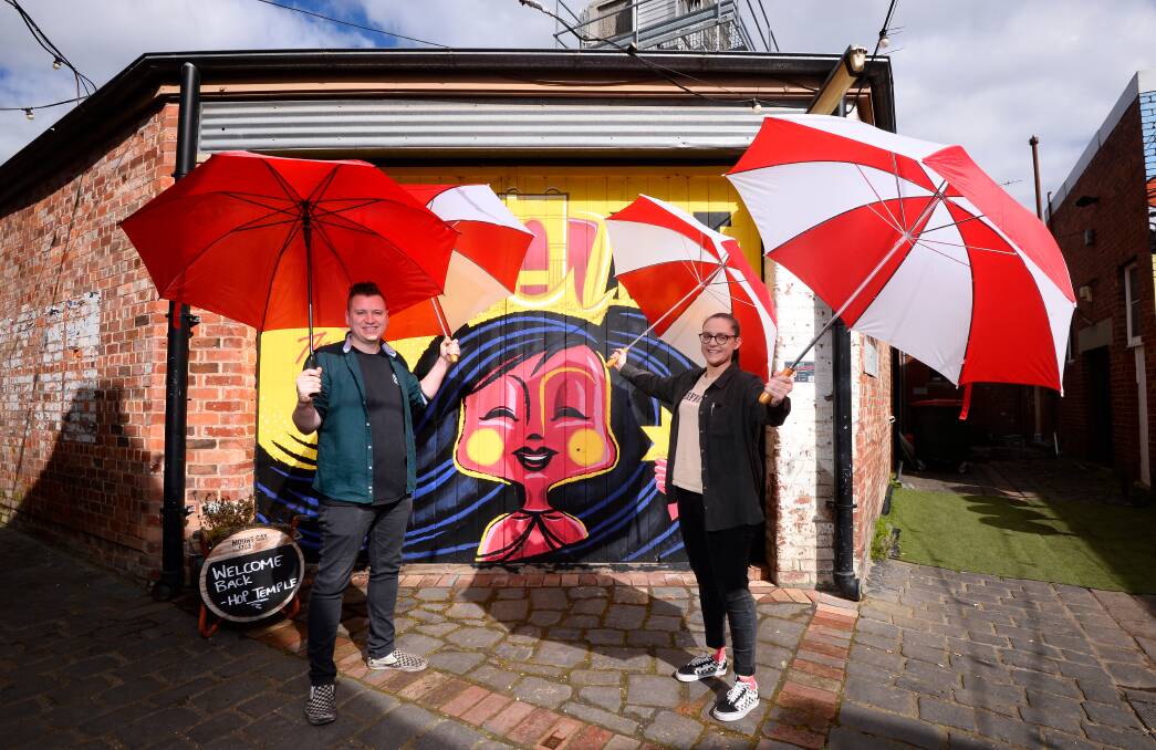 COLOUR: Hop Temple venue managers Toni Miller (right) and Joe Hirons with some of the leftover umbrellas from the laneway - but the popular tourist attraction needs help from the public to continue. Picture: Adam Trafford
