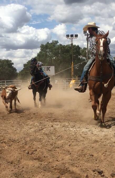 TEAMWORK: Spencer Donald riding Jet (black horse) with a fellow rodeo competitor in a team roping event.
