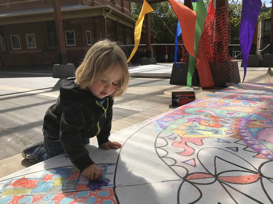 COLOUR: Alfie, 3, channels his own creativity as he helps complete a community mandala in Alfred Deakin Place. Picture: Michelle Smith