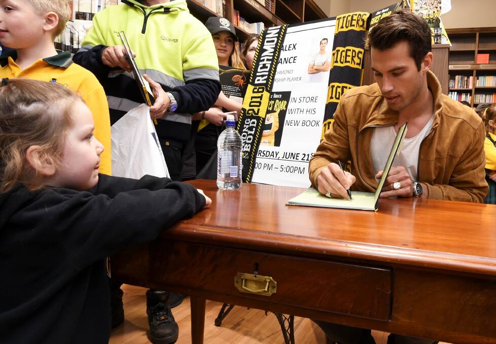 TIGERLAND: Richmond premiership player Alex Rance signs a copy of Tiger's Roar for Megan, 3, who waited 2 1/2 hours to meet her idol. Picture: Lachlan Bence