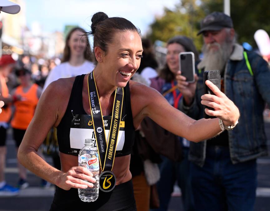 Women's marathon winner Ella McCartney facetimes her children after crossing the finish line of the Ballarat Marathon.