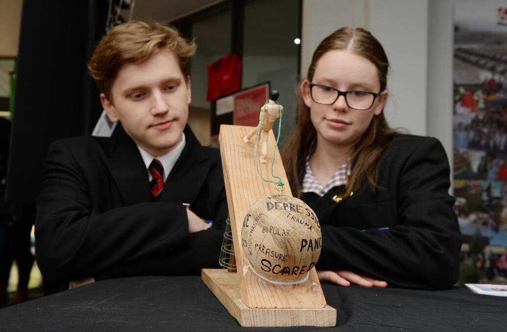 STRUGGLE: Mount Clear College 2019 school captains Peter Davies and Morgan Di Domenico with a student-created artwork depicting the struggle of mental health issues. Picture: Kate Healy
