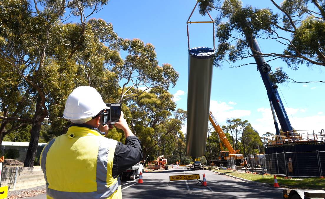 GOING UP: A worker captures the raising of a 23m tall wind turbine training tower at Federation University's Mount Helen campus. Picture: Adam Trafford