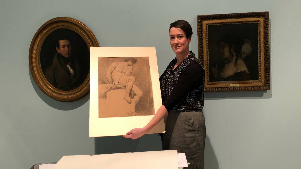 CLASSIC: Art Gallery of Ballarat curator Julie McLaren holds a drawing by Jacques Louis David c. 1770 in front of a work from Delacroix (left) and Gustave Courbet (right) which is in town for the Into Light exhibition.