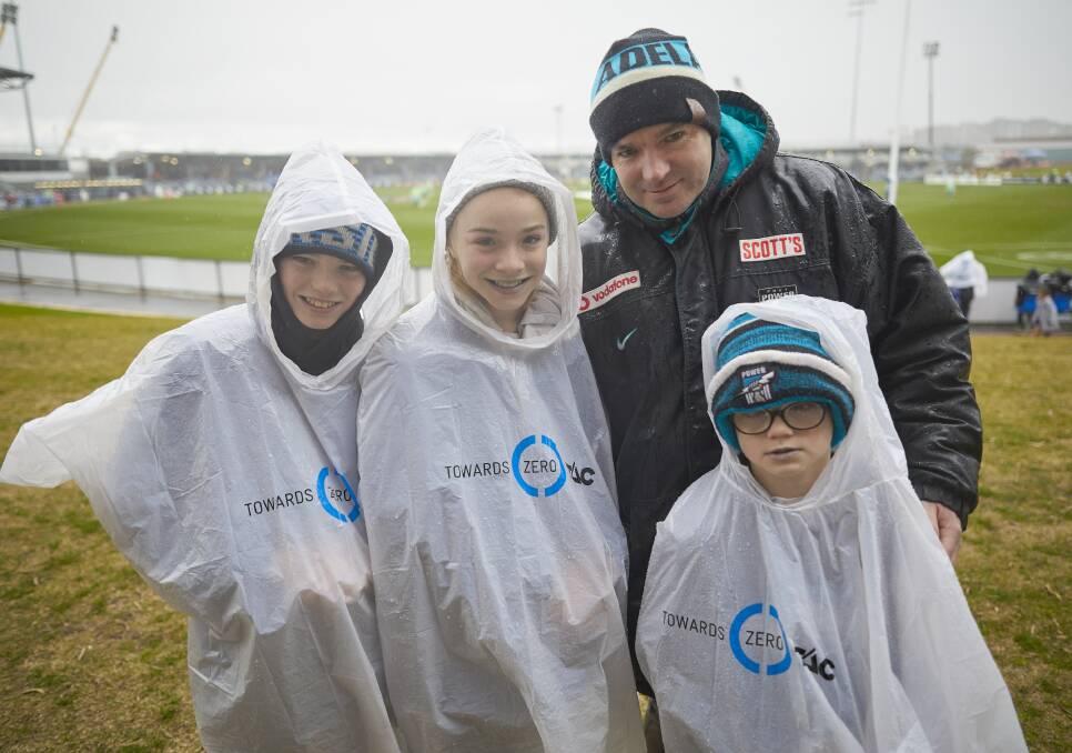 WET: The Curran family of Oscar, 13, Sophie, 11, dad Paddy and Archie, 8, took shelter in their ponchos in front of the scoreboard before the first bounce.
