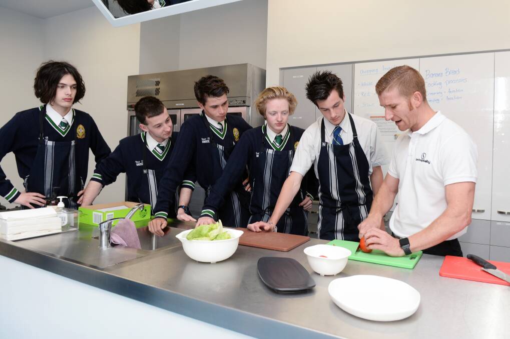 LOOKING SHARP: Hospitality trainer LeRoy Hand demonstrates basic knife skills to St Patrick's College students as they prepare a club sandwich during week one of their kitchen skills course. Picture: Kate Healy