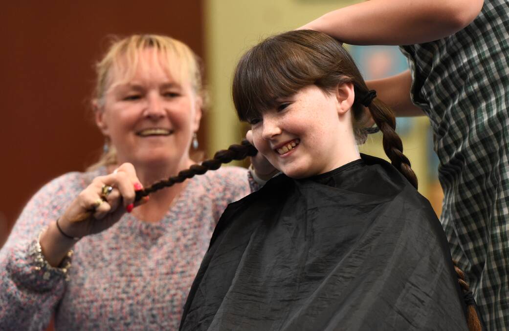 Kylie Scofield plaits daughter Abbie's hair one last time before the plaits were chopped off. Picture by Adam Trafford