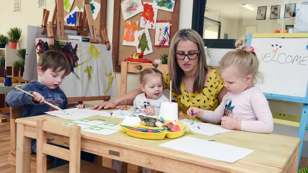 PASTING: Carter, 3, Millie, 18 months, centre owner Mageda Charrouf, and Aurelia, 3, enjoy craft at Sesame Kids. Ms Charrouf opened the centre to support families with children on the autism spectrum. Picture: Kate Healy