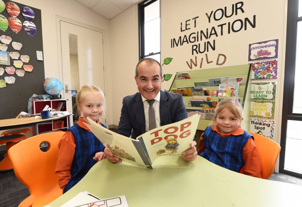 TOP MARKS: State education minister James Merlino takes time out in the book corner to read Top Dog to Siena Catholic Primary School prep students Eloise Hertnan and Amelia Loader following a tour of the new school. Picture: Jeremy Bannister
