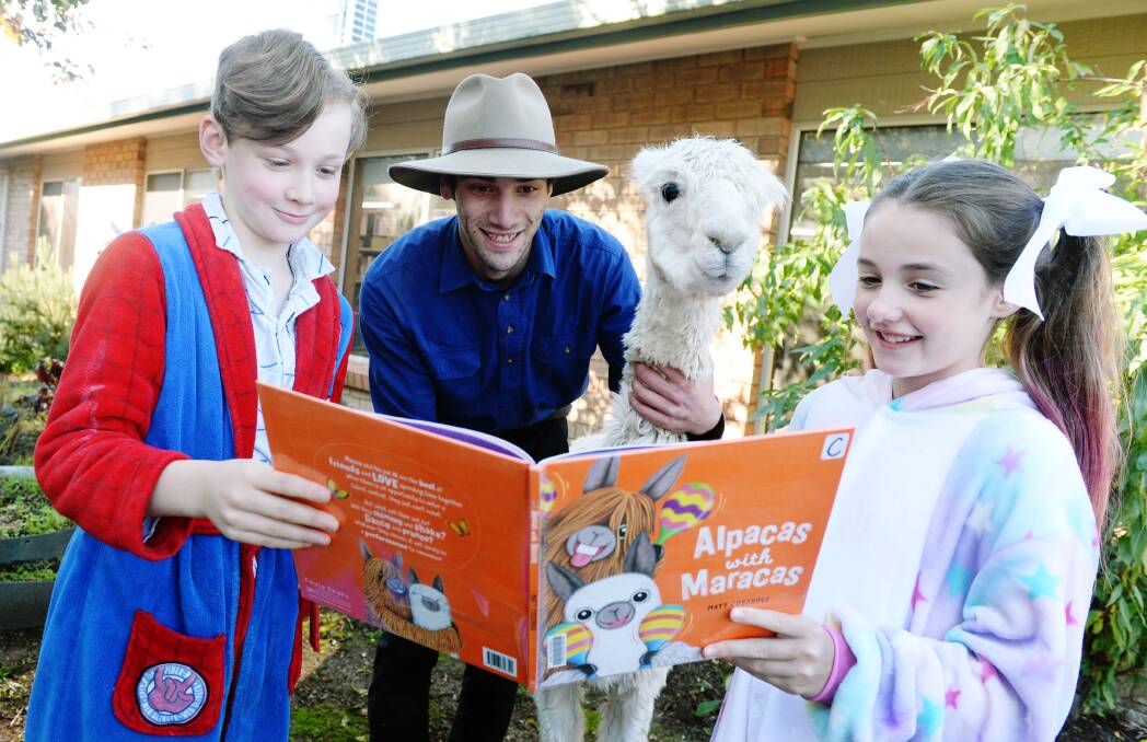 READERS: Ballarat Christian College year five students Chris and Ashleigh read Alpacas with Maracas with Cam Torresi from the Creswick Woollen Mill and Millhouse the alpaca. Picture: Kate Healy
