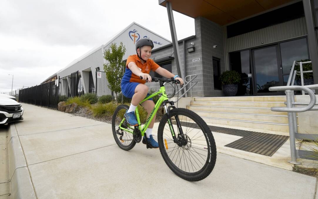 COMMUTE: Will takes his wheels for a spin outside Siena Catholic Primary school. Picture: Lachlan Bence