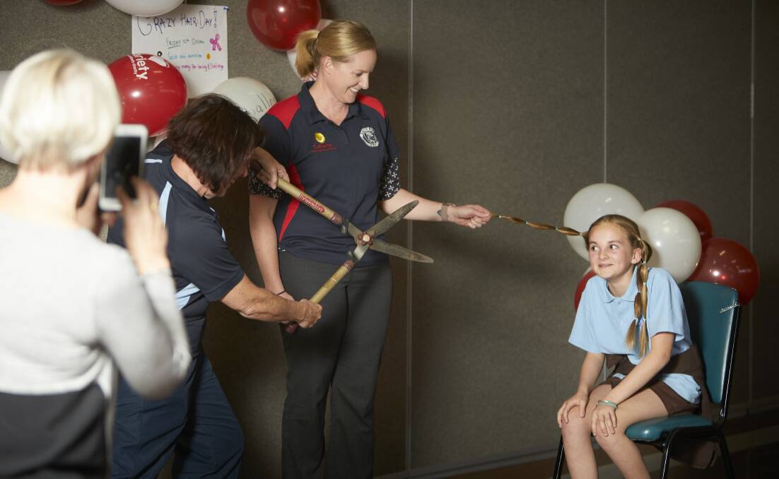 WAITING: St Thomas More pupil Tegan Pickles eyes off the oversized scissors as she prepares to lose her long hair to wigs for children with cancer, and to raise money for cancer support networks. Picture: Luka Kauzlaric