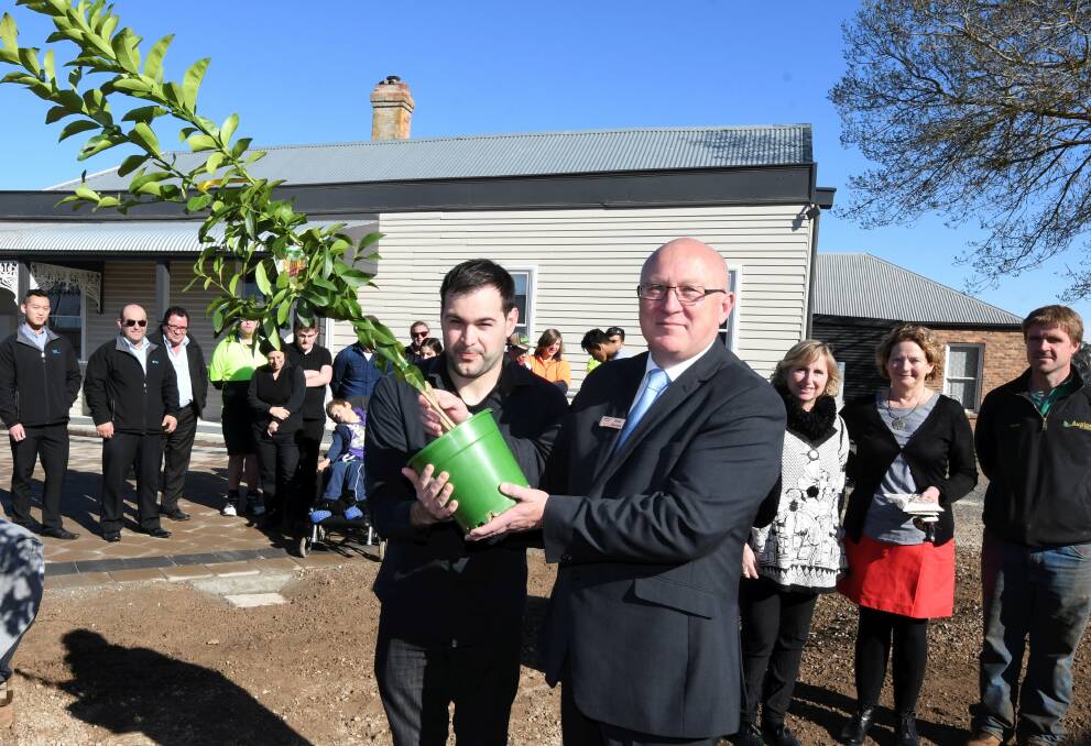 FRUIT: Brian Harrison hands over his 500th donated tree to Andrew Gear from Pinarc, who now have an orchard at Bonshaw. Picture: Lachlan Bence